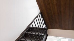 Una escalera con barandilla de metal, pasamanos de madera y un ventanal en la parte inferior.