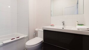 Een moderne badkamer met een wit toilet, een wastafel met spiegel en een handdoek op het aanrecht.