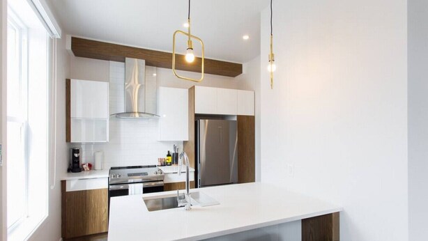 Een moderne keuken met een groot eiland, roestvrijstalen apparatuur en hanglampen.