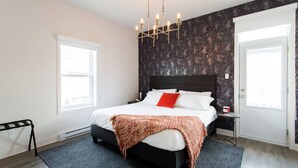 A modern bedroom with a black headboard, white bedding, a red pillow, and a patterned throw blanket. - Brand New Light filled Mile End Flat by Denstays (Montréal)
