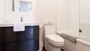 A bathroom with a white sink, a toilet, and a shower area. - Brand New Light filled Mile End Flat by Denstays (Montréal)
