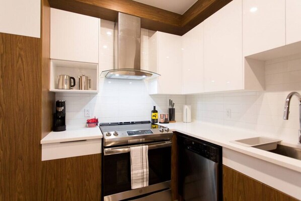A modern kitchen with white cabinets, stainless steel appliances, a built-in oven, and a dishwasher. - Live Like a Local in this Superb Loft by Denstays (Montréal)