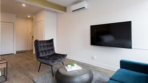 Una sala de estar moderna con un sillón de cuero negro, una mesa de centro redonda y un televisor de pantalla plana montado en la pared.