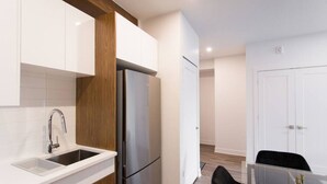 Una cocina moderna con muebles blancos, un refrigerador de acero inoxidable y una pared de acento de madera.