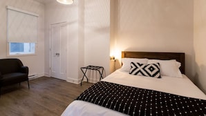 A bedroom with a bed, a chair, a small table, a window, and a door. - Huge 2 Bdr with Balcony in Mile End by Denstays (Montréal)