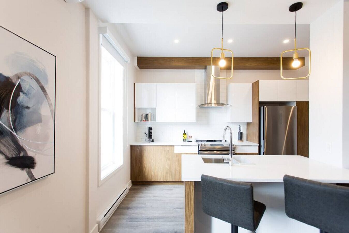 A modern kitchen with white cabinets, a stainless steel refrigerator, and a wooden accent wall.
