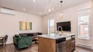 Une cuisine moderne dotée d’un îlot central, d’un lave-vaisselle encastré et d’un téléviseur à écran plat placé au-dessus de l’évier.