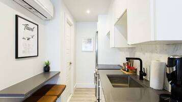 A modern kitchen with a built-in oven, a coffee machine, and a sink.