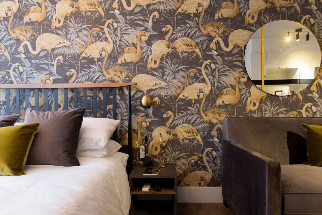 Una habitación de hotel con cama, mesita de noche y espejo.