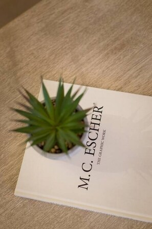 Kirja, jonka nimi on ”M. C. Escher”, ja jonka päällä on vihreä kasvi.
