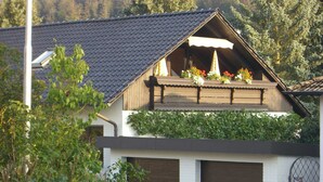 A house with a sloped roof, a balcony with flowers, and a garage.
