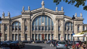 A grand building with classical architecture, featuring large arched windows and statues on the facade.