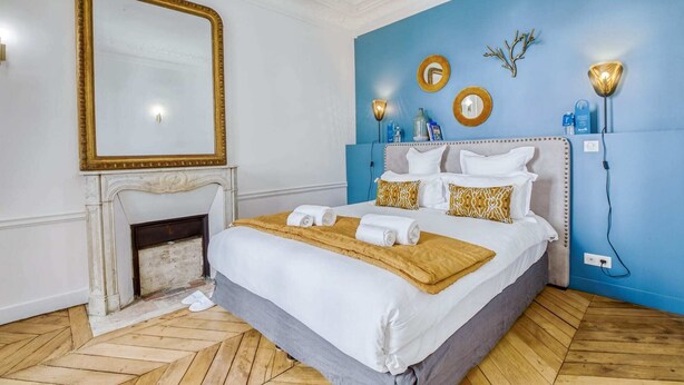 Une chambre à coucher avec un grand lit, une cheminée et un mur d’accent bleu.