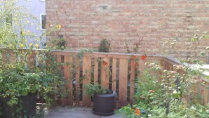 A wooden deck with potted plants and a brick wall in the background. - Historisches Bürgerhaus Coburg (Coburg)