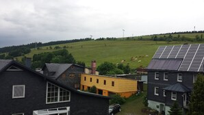 Paisatge rural amb un camp verd, alguns edificis i una instal·lació de panells solars.