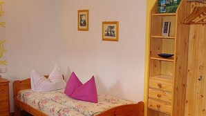 Un dormitori amb un llit i un armari de fusta, i dos quadres penjats a la paret.