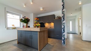 Een moderne keuken met grijze kastjes, een houten kookeiland en een raam met zonwering.
