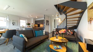 Een moderne woonkamer met een bank, salontafel en een trap.