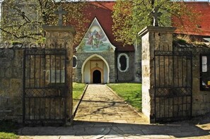 Um edifício de pedra com telhado vermelho, uma porta central em arco e um mural acima.