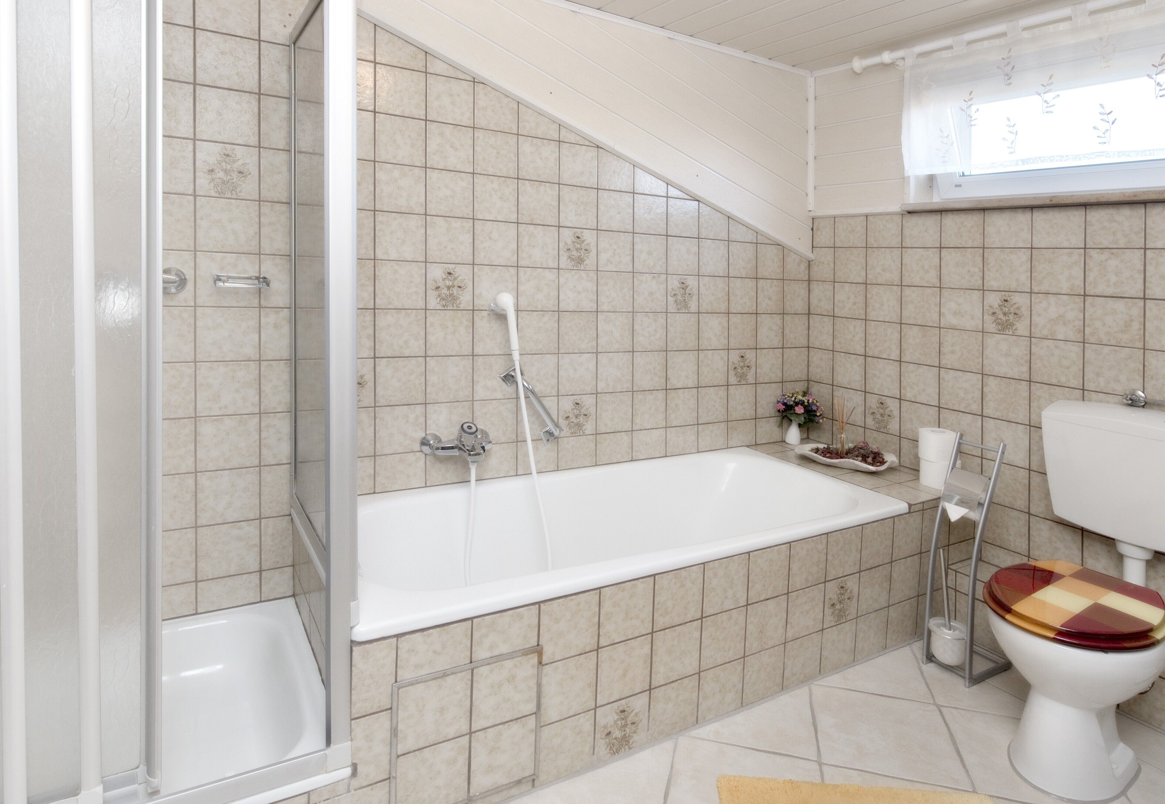Une salle de bain équipée d’une douche, d’une baignoire, de toilettes et d’une fenêtre.