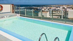A clear blue pool with a glass barrier, a lifebuoy, and a sign indicating no diving or jumping. - Casa Rafa El Cotillo (El Cotillo)