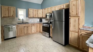 Una cocina con armarios de madera, un refrigerador de acero inoxidable, un horno y un lavavajillas.