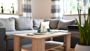 A modern living room with a grey sofa, a wooden coffee table, and a potted plant.