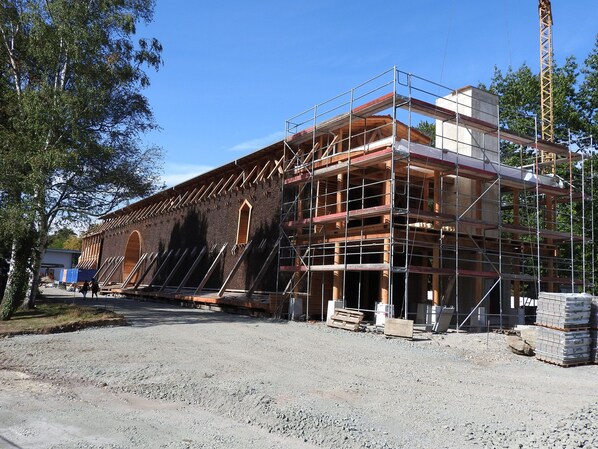 A building under construction with scaffolding, a brick facade, and a large arched window.
