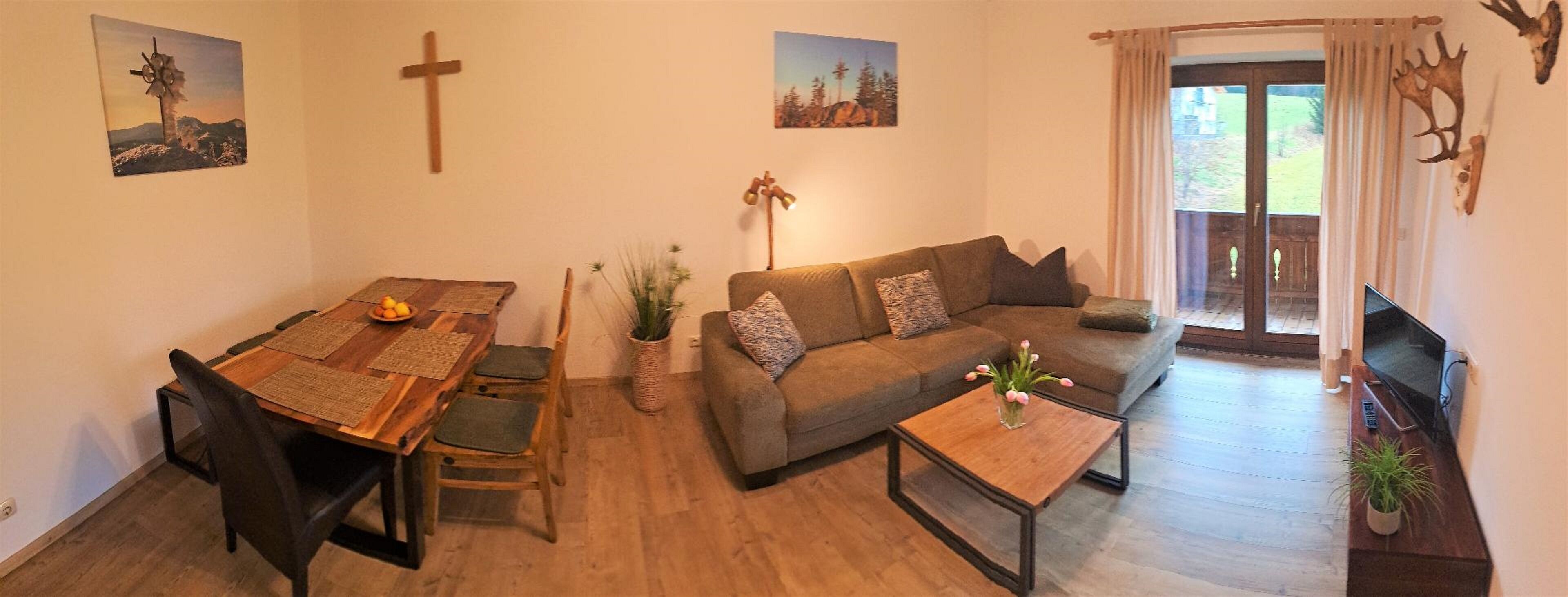 A cozy living room with a wooden dining table, a sofa, and a TV.