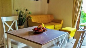 Ein Essbereich mit einem Tisch für zwei Personen, einem gelben Sofa und einer Topfpflanze.