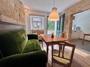 A cozy room with a green sofa, wooden dining table, and a view of greenery outside. - Residenz Nr.6 (Zapfendorf)