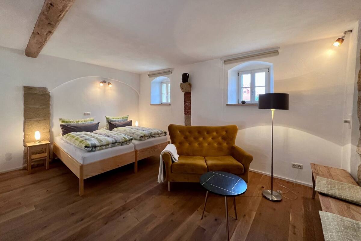 A cozy room with a bed, a sofa, a small table, and a lamp.