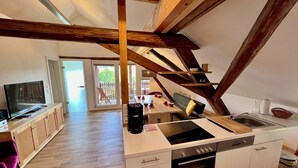 A modern kitchen with a central island, built-in oven, and a dining area with a table and chairs. - Residenz Nr.6 (Zapfendorf)