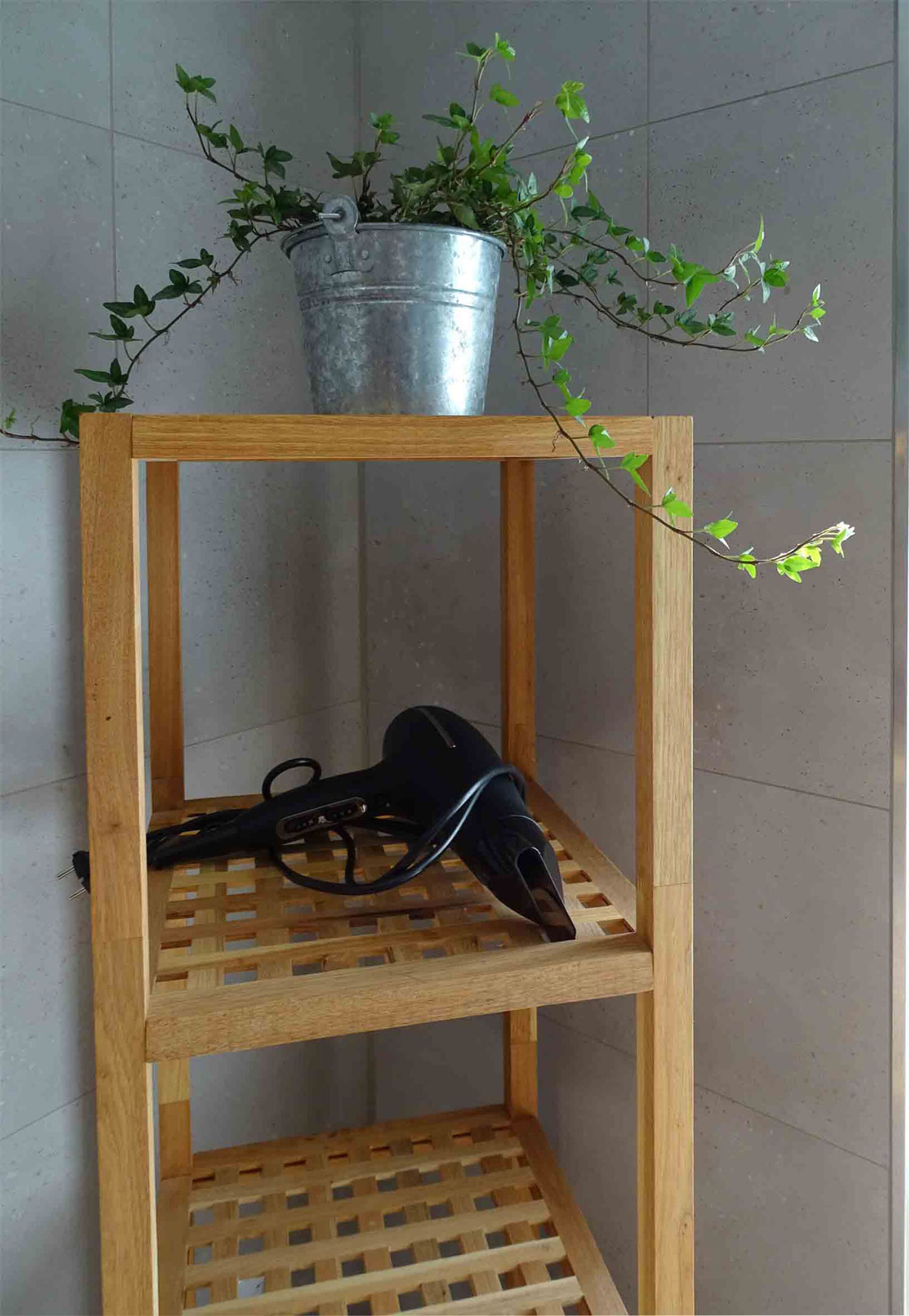 Una repisa de madera con un cubo metálico que contiene una planta.