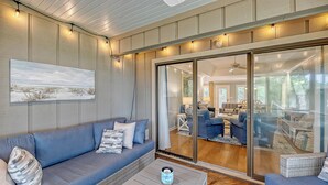 A modern living room with a blue sofa, a coffee table, and a large glass door leading to another room.