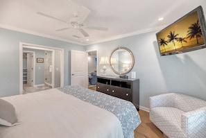 A bedroom with a bed, a dresser, a mirror, and a TV.