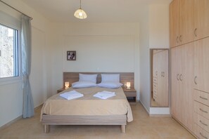 A bedroom with a bed, nightstands, a wardrobe, and a window with curtains.