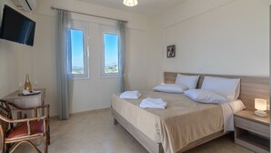 A hotel room with a bed, bedside table, chair, TV, window, and curtains.
