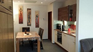 A compact kitchen with a dining area, wooden cabinets, and a coffee maker. - Ferienwohnung Michaela (Winterberg)
