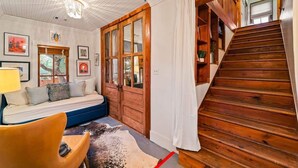 Una habitación con una escalera de madera, un sofá y una alfombra.