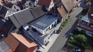 Vista aérea de una casa moderna de dos pisos con techo inclinado, paneles solares y un garaje visible.