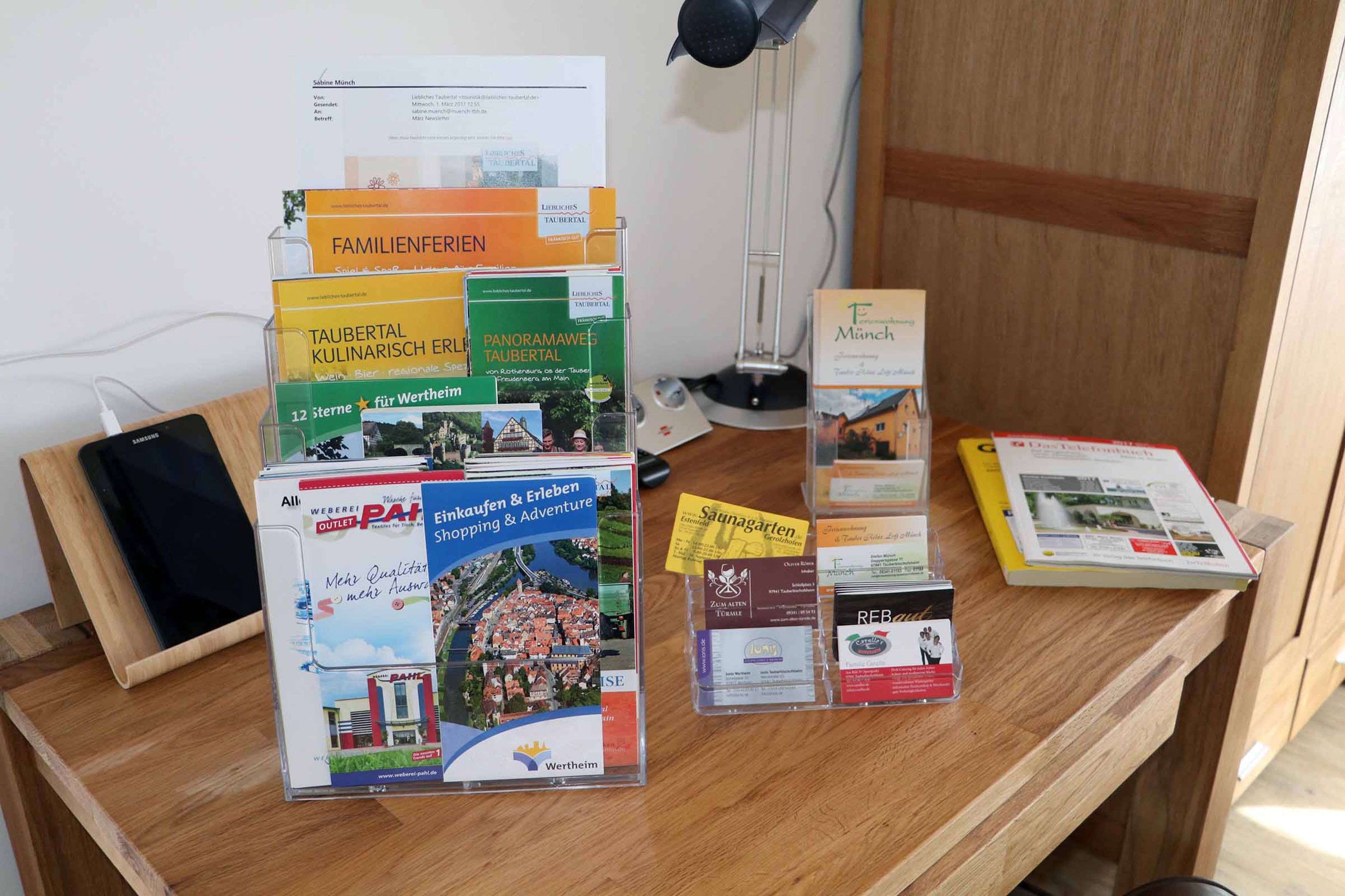 A wooden desk with various travel brochures and a laptop.