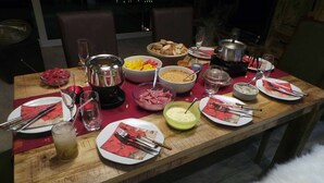 Una mesa de comedor dispuesta con diversos platos, utensilios y una olla caliente.