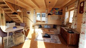 Interior acogedor de una cabaña con detalles de madera, un comedor, un sofá y una escalera.