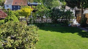 A residential garden with a well-maintained lawn, a variety of shrubs, and a wooden fence. - Andy & Ida's Ferienwohnung (Neustadt an der Waldnaab)