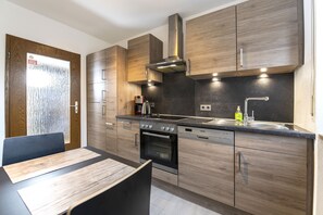 A modern kitchen with wooden cabinets, a stainless steel range hood, and a built-in oven. - Andy & Ida's Ferienwohnung (Neustadt an der Waldnaab)