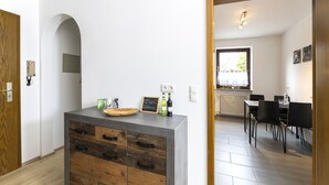 A modern kitchen with a wooden cabinet, a small island, and a dining area with chairs and a table. - Andy & Ida's Ferienwohnung (Neustadt an der Waldnaab)