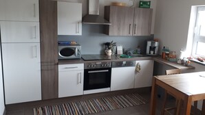 Una cocina moderna con armarios blancos y de madera, microondas, estufa, horno y pileta.