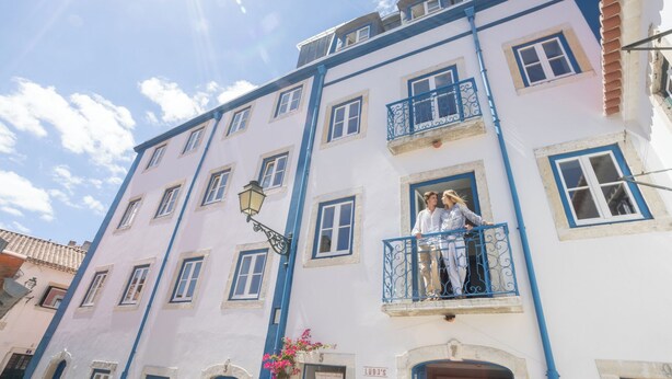 Un immeuble à plusieurs étages doté de balcons, d’un lampadaire et d’une jardinière.