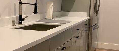 Una cocina moderna con un lavamanos doble, electrodomésticos de acero inoxidable y armarios grises.